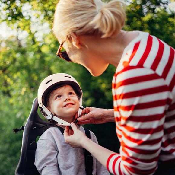 donna che allaccia il casco a un bambino in bici | Crédit Agricole