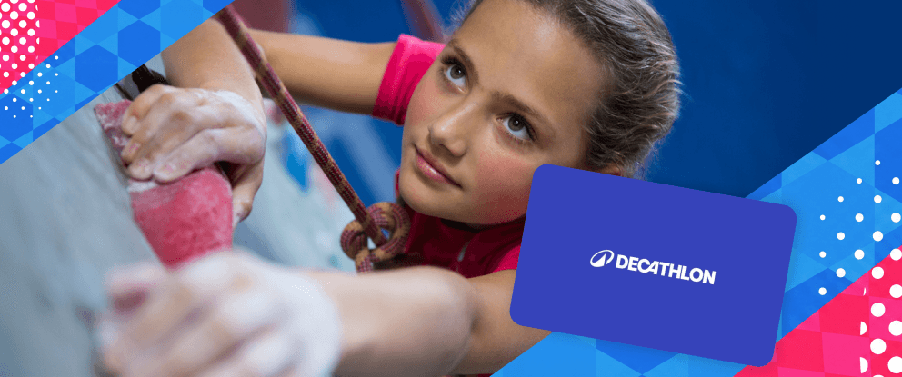 Primo piano di una bambina durante una sessione di arrampicata indoor; sulla destra è presente una gift card Decathlon. | Crédit Agricole Primo piano di una bambina durante una sessione di arrampicata indoor; sulla destra è presente una gift card Decathlon. | Crédit Agricole