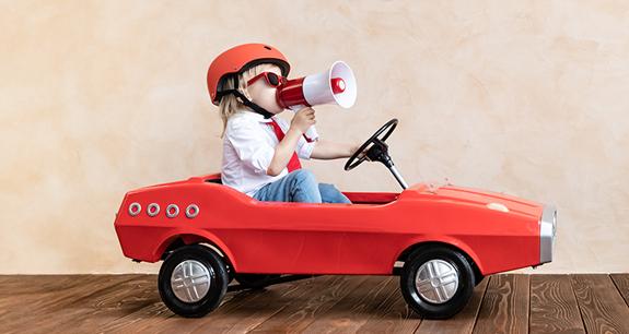 bambino su un'auto giocattolo con casco e megafono | Crédit Agricole bambino su un'auto giocattolo con casco e megafono | Crédit Agricole