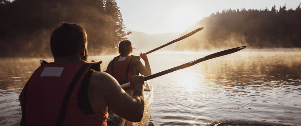 Due persone in canoa su un lago immerso nella natura al tramonto | Crédit Agricole Due persone in canoa su un lago immerso nella natura al tramonto | Crédit Agricole