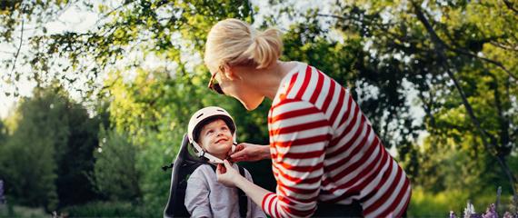 donna che allaccia il casco a un bambino in bici | Crédit Agricole
