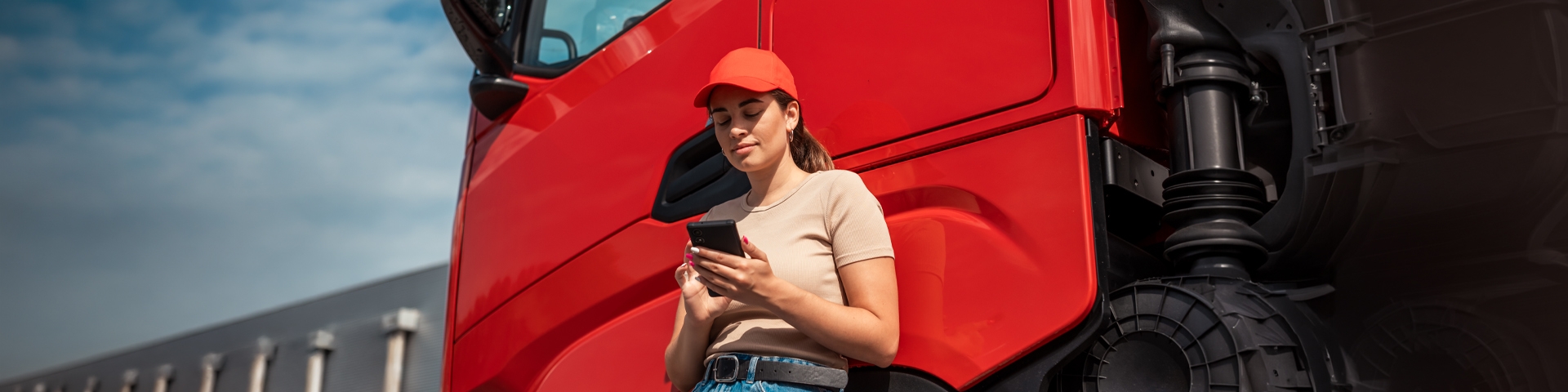 Rgazza che guarda il telefono appoggiata a un camion | Crédit Agricole Rgazza che guarda il telefono appoggiata a un camion | Crédit Agricole