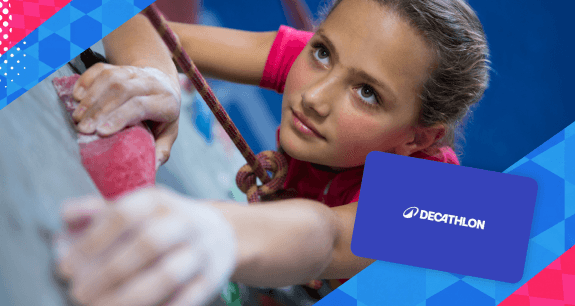 Primo piano di una bambina durante una sessione di arrampicata indoor; sulla destra è presente una gift card Decathlon. | Crédit Agricole Primo piano di una bambina durante una sessione di arrampicata indoor; sulla destra è presente una gift card Decathlon. | Crédit Agricole