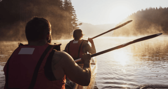 Due persone in canoa su un lago immerso nella natura al tramonto | Crédit Agricole Due persone in canoa su un lago immerso nella natura al tramonto | Crédit Agricole
