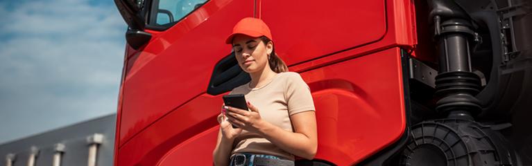Rgazza che guarda il telefono appoggiata a un camion | Crédit Agricole Rgazza che guarda il telefono appoggiata a un camion | Crédit Agricole