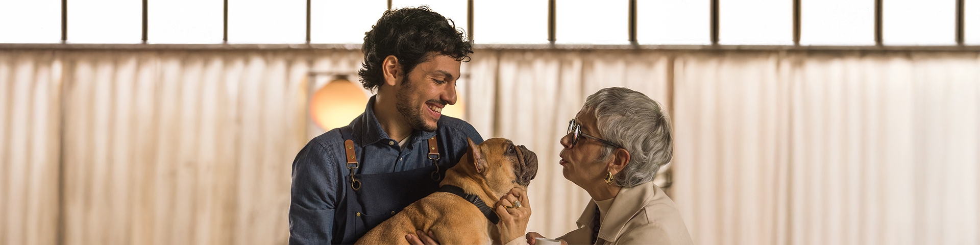 una signora anziana che da un bacio al cane che è tenuto in braccio da un uomo | Crédit Agricole una signora anziana che da un bacio al cane che è tenuto in braccio da un uomo | Crédit Agricole